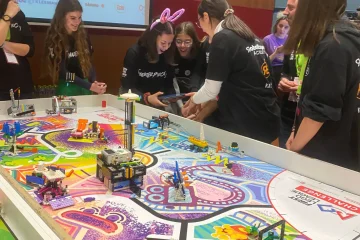 Ομάδα κοριτσιών διαγωνίζεται, κρατώντας ενα tablet για το χειρισμό του ρομποτ, ζώντας με ένταση την στιγμή